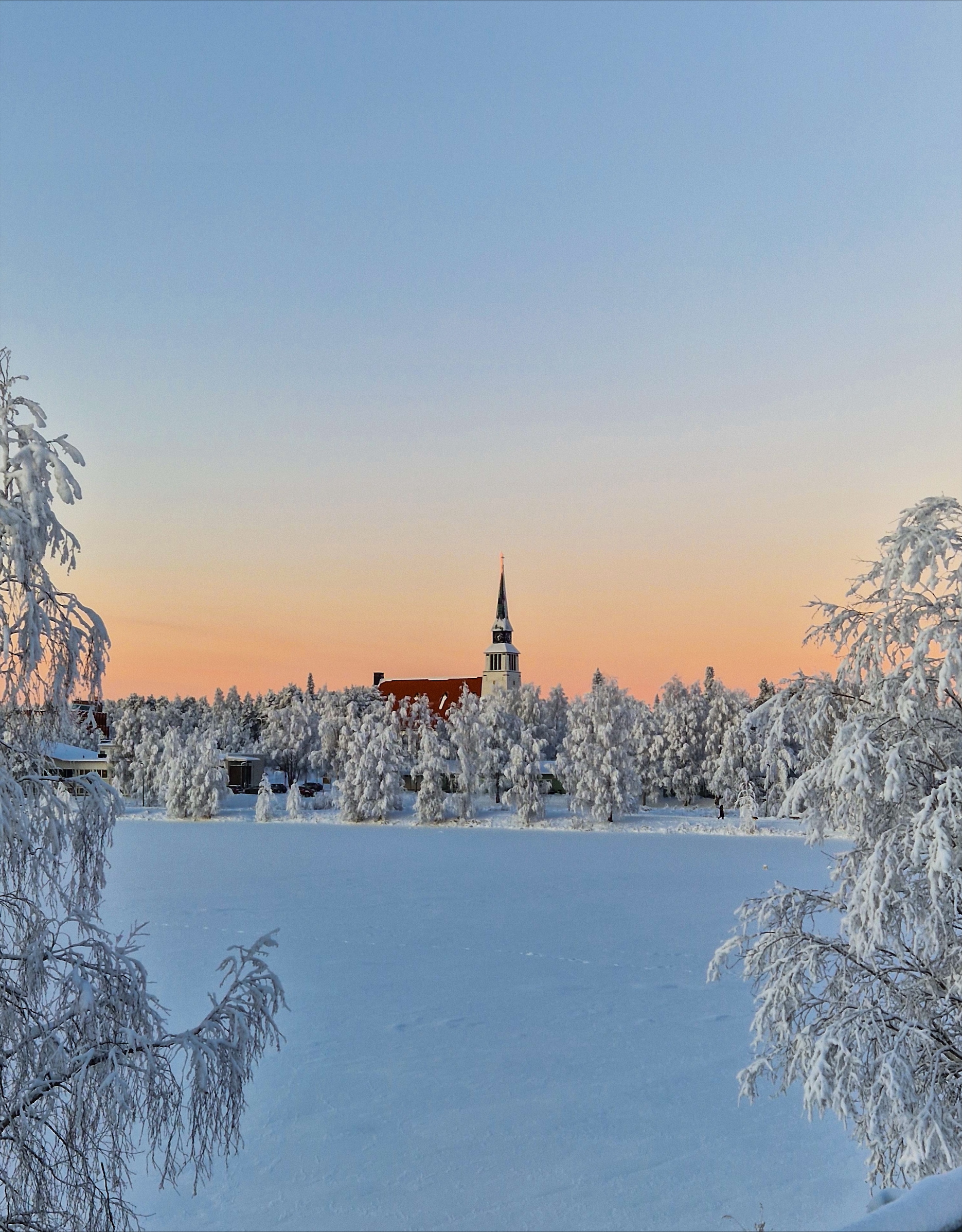 Jouluinen kuva Kemijärven kirkosta huurteisen puiden keskellä