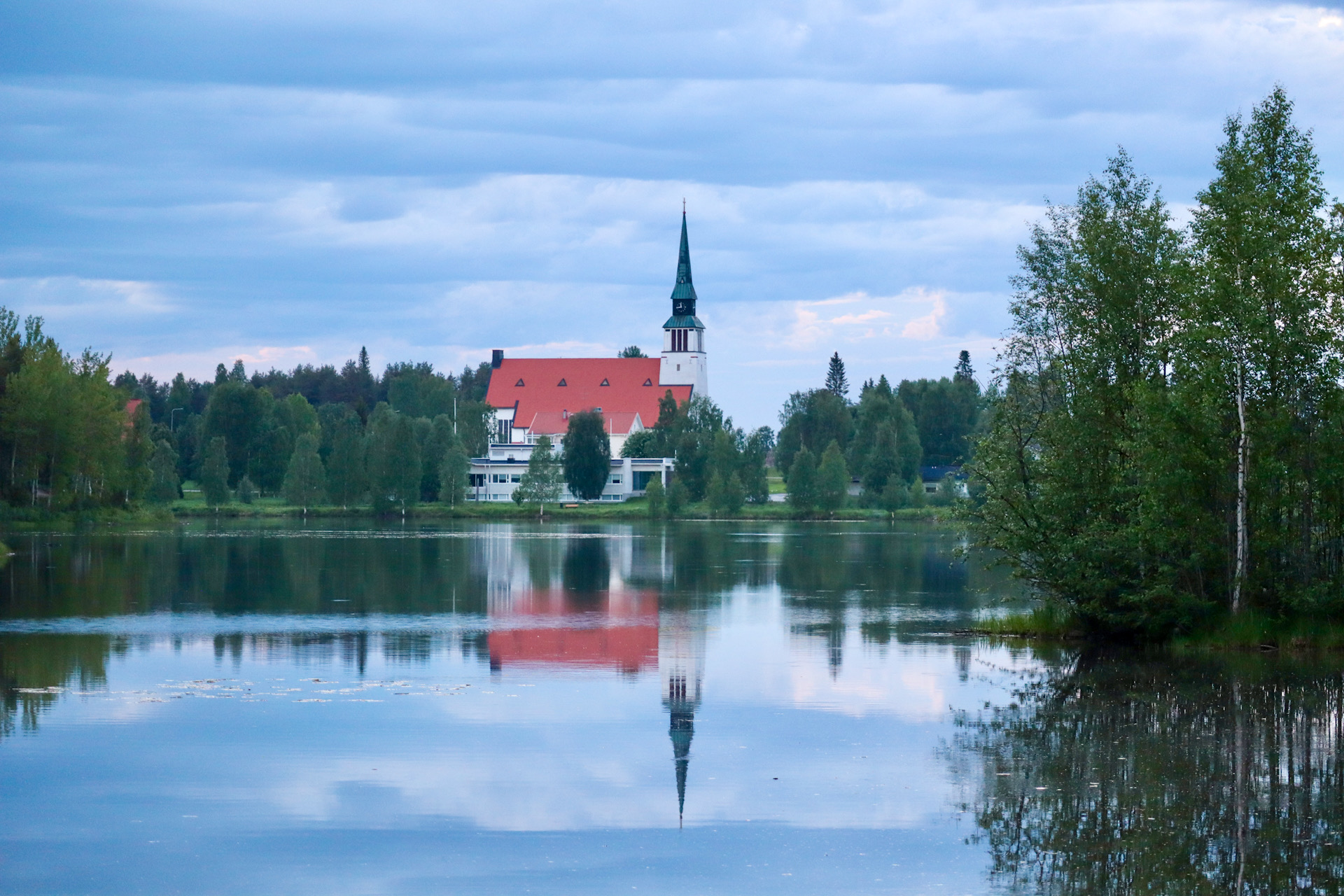 Kesäinen kuva Kemijärven kirkosta, joka peilautuu Kuumalampeen